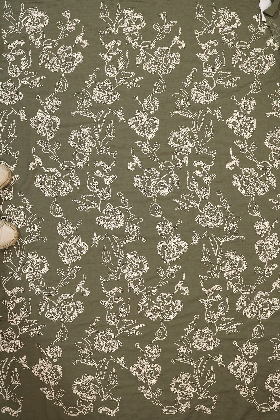 Repeating floral cotton cord embroidery pattern on olive green rayon fabric